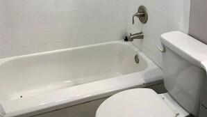 A bathroom with a white bathtub, a toilet, and a showerhead. - Capital City Condo #3 (Frankfort)