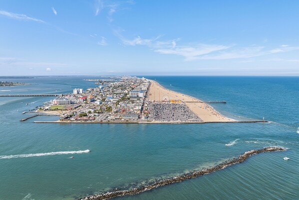 An aerial view of a coastal town with a beach, pier, and a Ferris wheel.