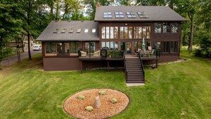 Une maison moderne à deux étages, dotée d’un patio couvert, d’un petit jardin et d’un escalier menant à l’étage supérieur.