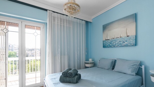 A bedroom with a bed, a nightstand, a painting, and a view through a window. - Fairytale, Nilie Hospitality MGMT (Thessaloniki)