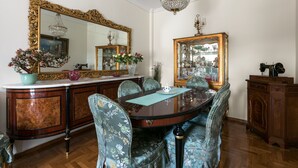 A dining room with a wooden table, floral chairs, a large mirror, and a chandelier. - Fairytale, Nilie Hospitality MGMT (Thessaloniki)