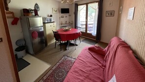 A compact living space with a kitchenette, a dining area, and a sofa. - Griou N°52 (Le Lioran)