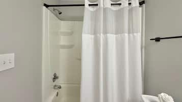 A bathroom with a shower, toilet, and a white curtain.