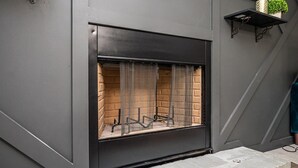 A modern fireplace with a metal screen, set against a grey wall with a brick pattern. - Renovated townhouse in Norcross (Norcross)