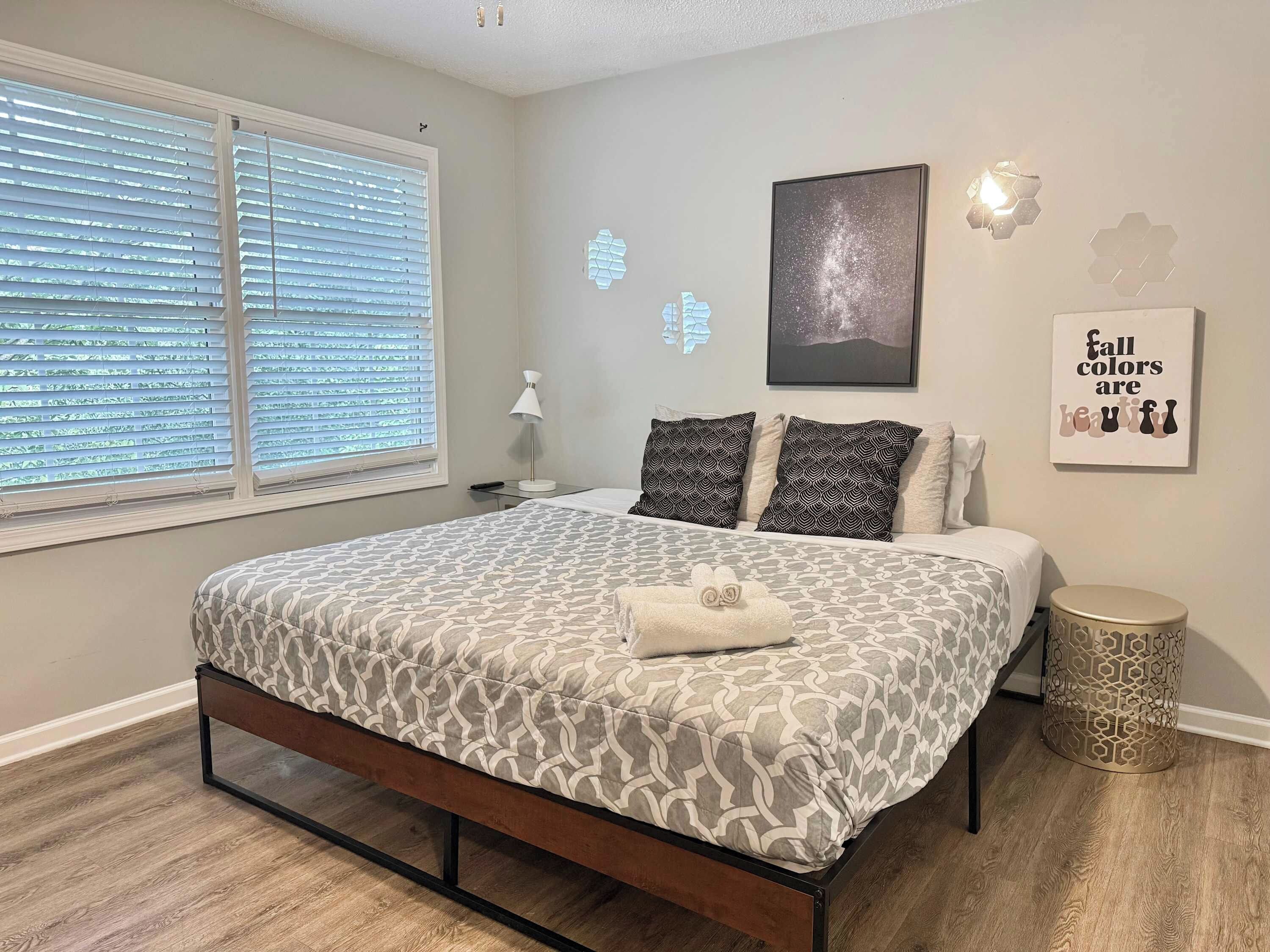 A bedroom with a bed, bedside table, lamp, and decorative wall art.