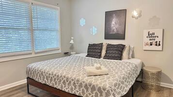 A bedroom with a bed, bedside table, lamp, and decorative wall art.