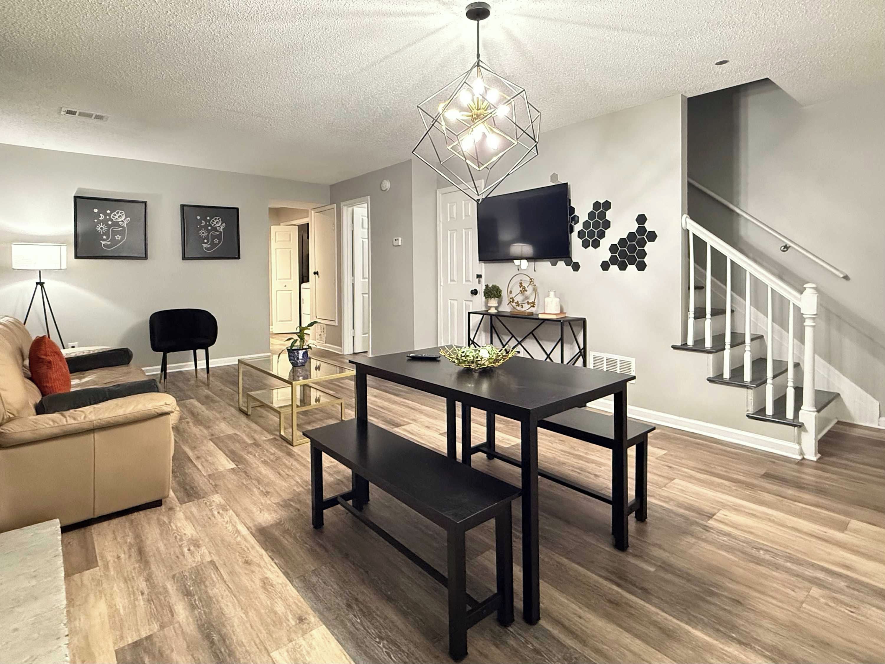 A modern living room with a dining table, sofa, and a staircase.