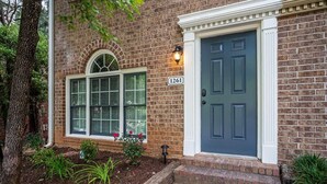 A brick house with a dark blue door, a number '1261' sign, and a welcome mat. - Renovated townhouse in Norcross (Norcross)