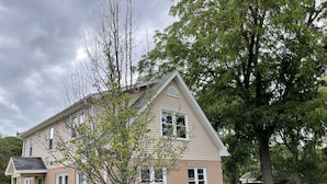 Una casa a due piani con tetto a falde, un portico e un prato ben curato.
