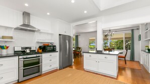 Une cuisine moderne avec des meubles blancs, des appareils en acier inoxydable et un îlot central.