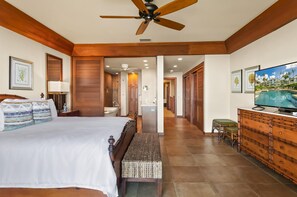 A hotel room with a bed, a television, a wooden dresser, and a bathroom visible through an open door.
