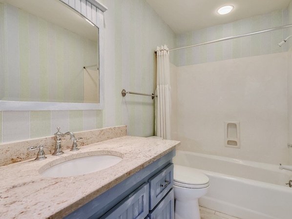 A bathroom with a sink, mirror, toilet, and bathtub.
