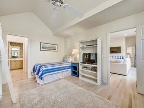Une chambre à coucher avec un lit, un bureau, une bibliothèque et un ventilateur de plafond.