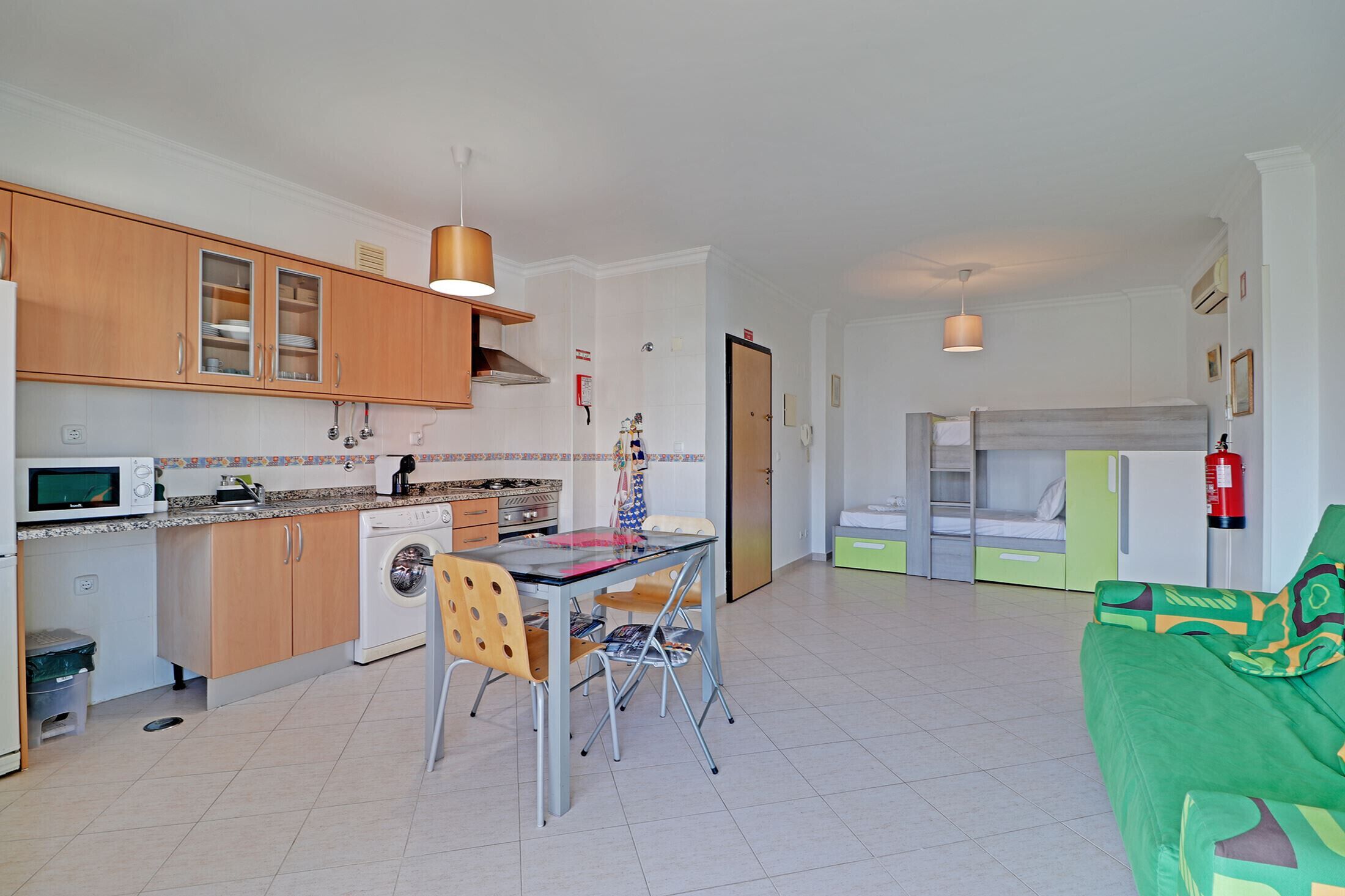 Uma cozinha compacta com mesa e cadeiras, máquina de lavar e micro-ondas.