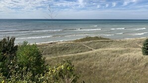 Paesaggio costiero con dune erbose, cielo sereno e l'oceano.
