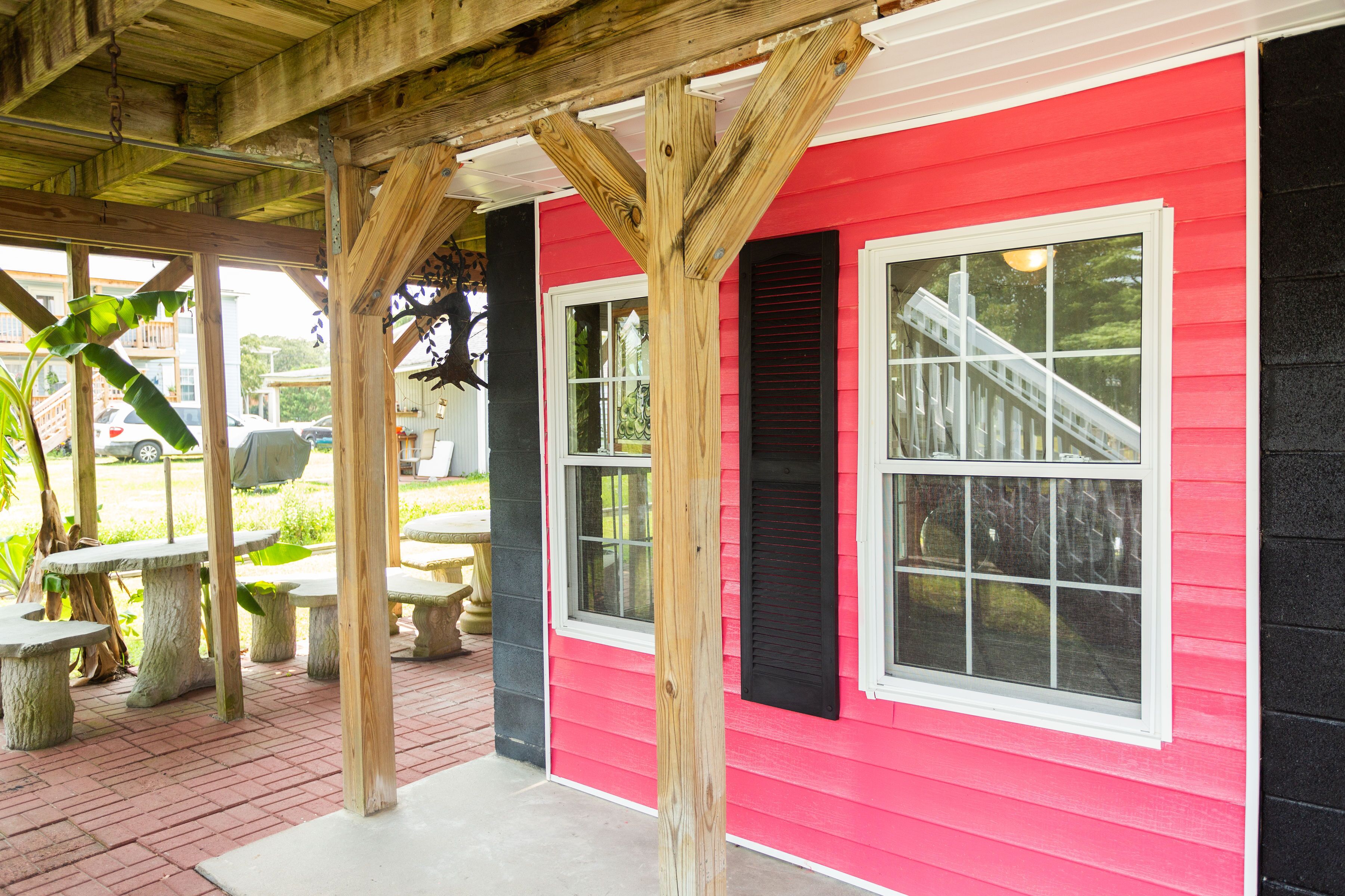 A red building with black shutters, stone benches, and a covered patio area.