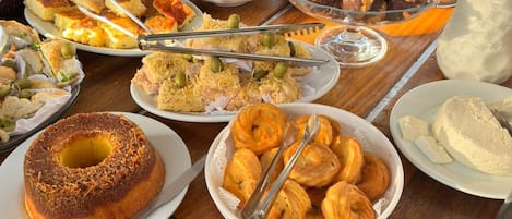 Una mesa de buffet con diversos platos, incluyendo pastelería, pan y postres.