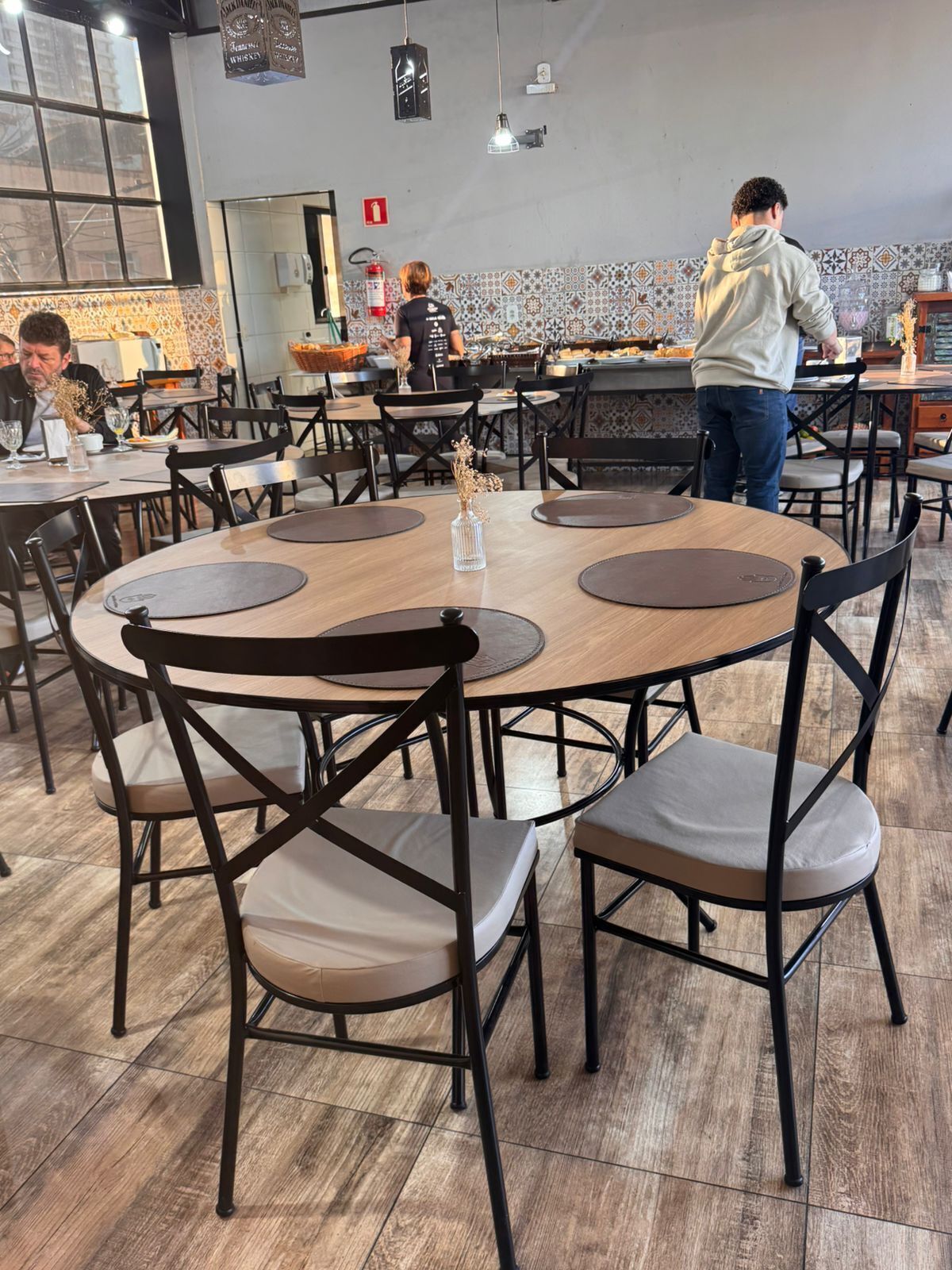 Un restaurante con mesas redondas, sillas negras y un revoque de azulejos.