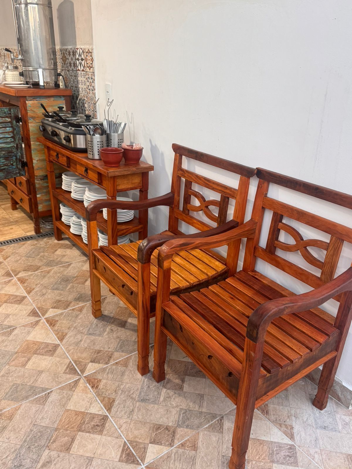 A wooden bench and table with a tiled floor and a wall with a decorative tile pattern.