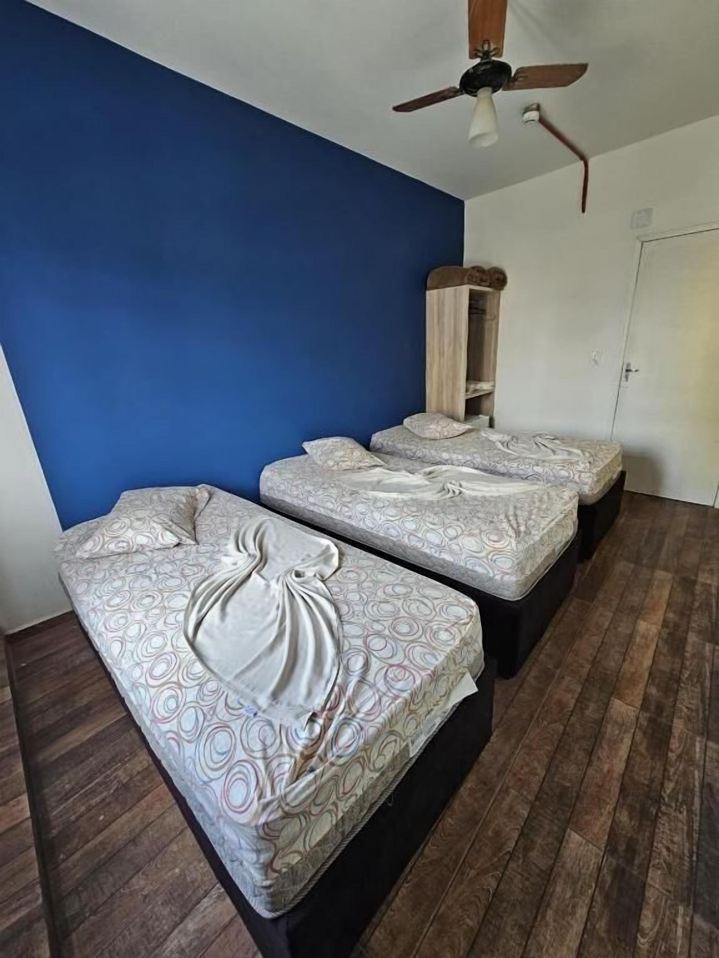 A room with two beds, a ceiling fan, and a wardrobe.