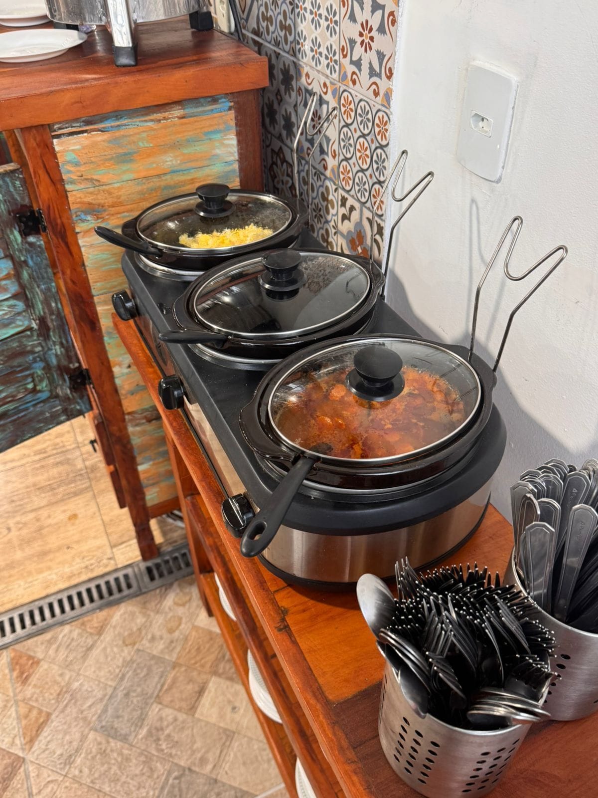 A kitchen with a stove, pots, and a colander with utensils.