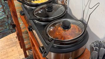 A kitchen with a stove, pots, and a colander with utensils.