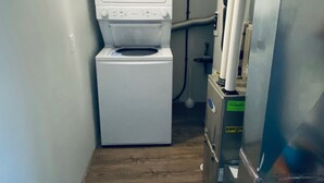 Un cuarto de lavandería con lavadora y secadora, un calentador de agua y una bomba de agua.
