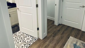 Un pasillo con puertas blancas, un suelo de madera y un tapete estampado.