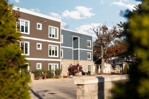 A multi-story residential building with a flat roof, multiple windows, and a parking area in front.