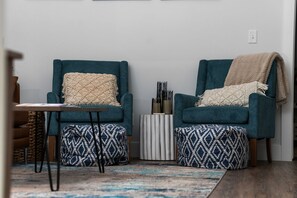 Un salón con dos sillones color turquesa, una mesita y un tapete estampado.