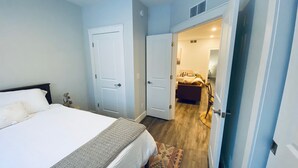 Un dormitorio con una cama, dos puertas y un pasillo que lleva a un baño.