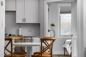 A modern kitchen with white cabinets, a granite countertop, and a dining area with wooden chairs.