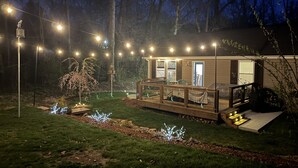 A house with a wooden deck, string lights, and a small garden. - Quiet & Chic 3 BR Cottage w/ Private Garden Near Downtown Asheville (Asheville)