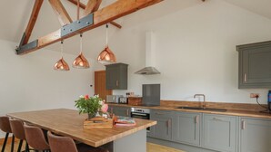 A modern kitchen with a wooden island, grey cabinets, and copper pendant lights. - Swallows Nest (Sturminster Newton)