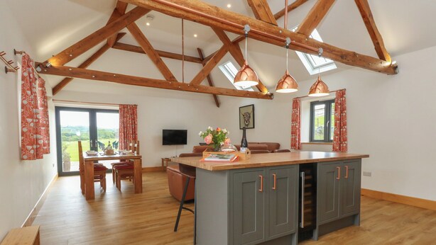 A spacious kitchen with a large island, wooden beams, and pendant lighting. - Swallows Nest (Sturminster Newton)