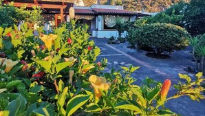 A building with a tiled roof and a garden with various plants and flowers. - La Magnolia Casa Vacanze (Sicilia)