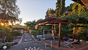A covered outdoor seating area with a pergola, lounge chairs, and a decorative sun pattern on the ground. - La Magnolia Casa Vacanze (Sicilia)