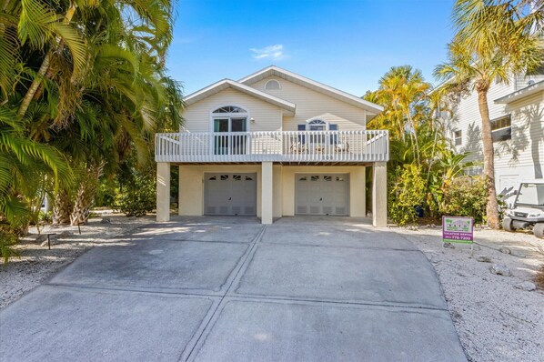 A two-story house with a balcony, a garage, and a driveway.
