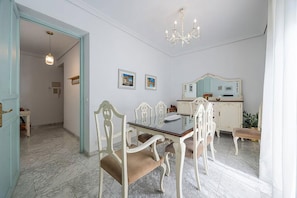 A dining area with a glass table, white chairs, and a chandelier. - Al-Andalus Stately Home Casa Atalaya Center (Cordoba)