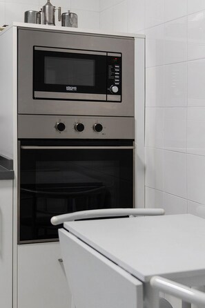 A compact kitchen with a built-in microwave and oven, a stainless steel range hood, and a white countertop. - Stately Home Casa Atalaya Center Córdoba (Cordoba)
