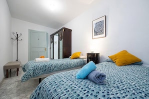 Una camera d'albergo con due letti, un armadio, un appendiabiti e un quadro appeso al muro.