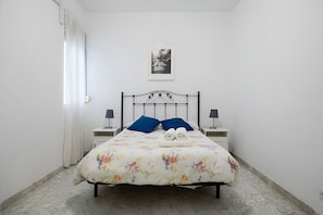 A single bed with a floral bedspread, two pillows, two bedside tables with lamps, and a framed picture on the wall. - Al-Andalus Stately Home Casa Atalaya Center (Cordoba)