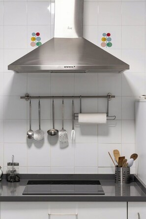A kitchen with a stainless steel range hood, hanging utensils, and a spice rack. - Al-Andalus Stately Home Casa Atalaya Center (Cordoba)