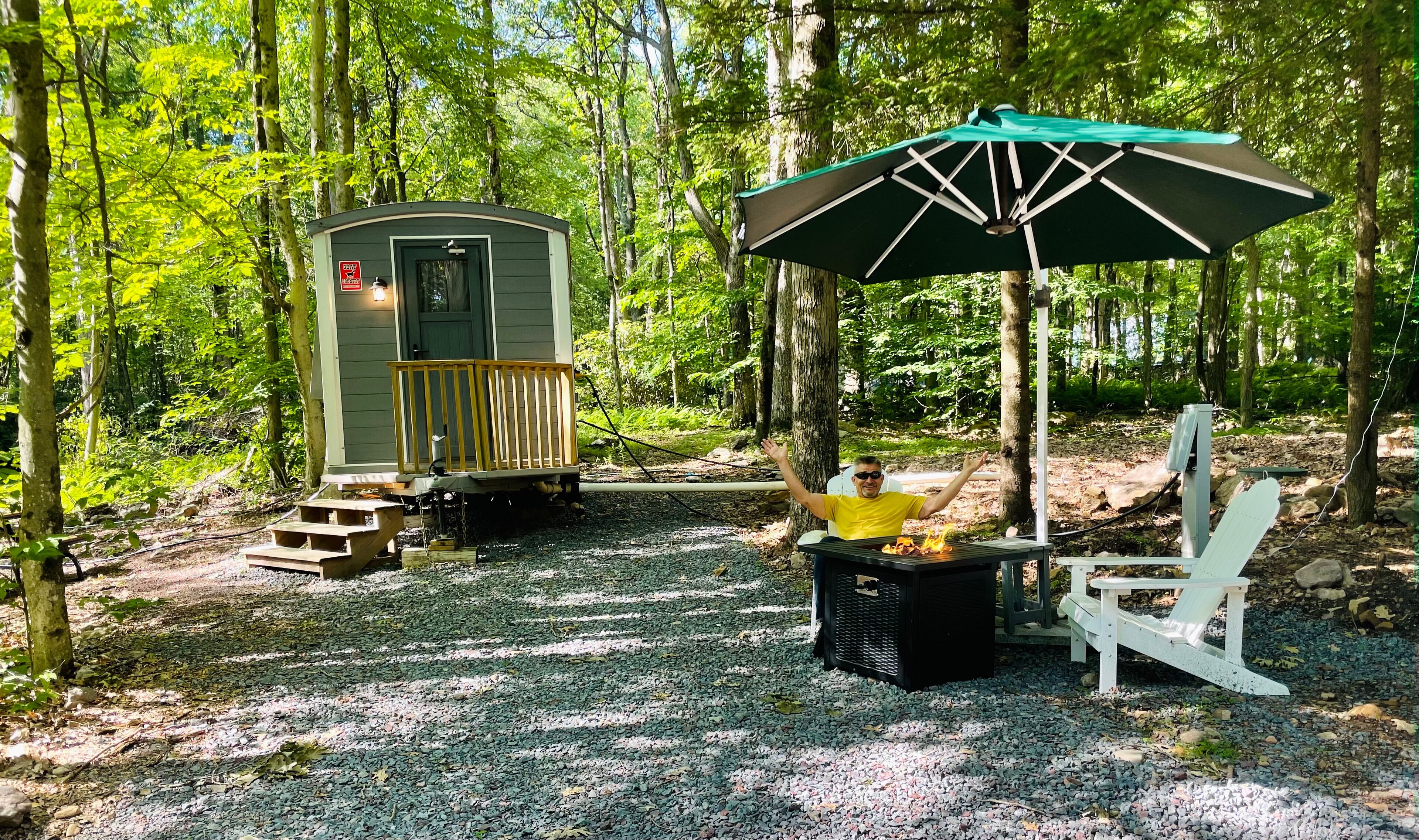 A campsite with a portable toilet, a fire pit, and a picnic table.