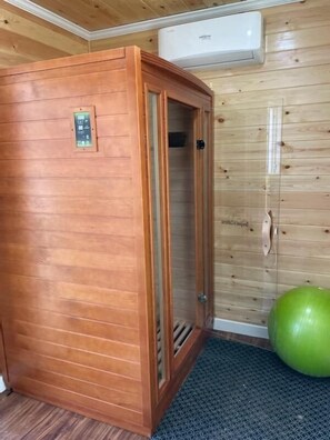 Uma sala de sauna com paredes de madeira, uma porta e um painel de controle.