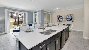 A modern kitchen with a large island, double sink, and black cabinets. - EV_2861 - 4BR / 3BA Storey Lake Townhome near to Disney, Private Pool & Resort (Kissimmee)