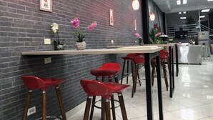A modern bar area with a brick wall, red bar stools, and pendant lighting.