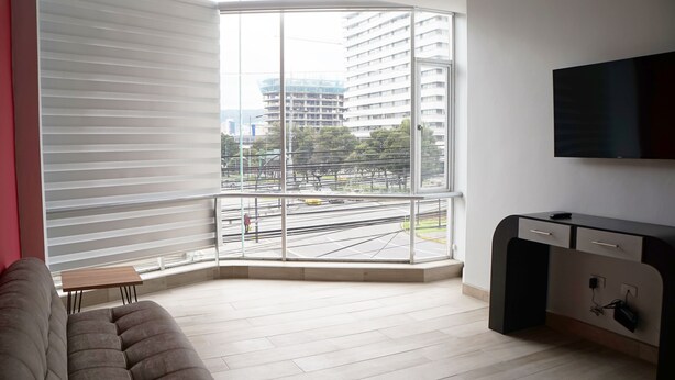 A modern living room with a large window, a flat-screen TV, and a sofa.