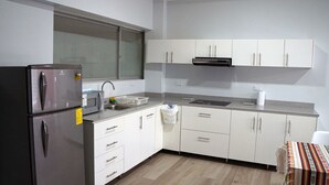A compact kitchen with a refrigerator, microwave, sink, and white cabinets.