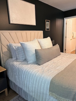 Relax in a serene bedroom with a large bed, tufted headboard, and elegant artwork.